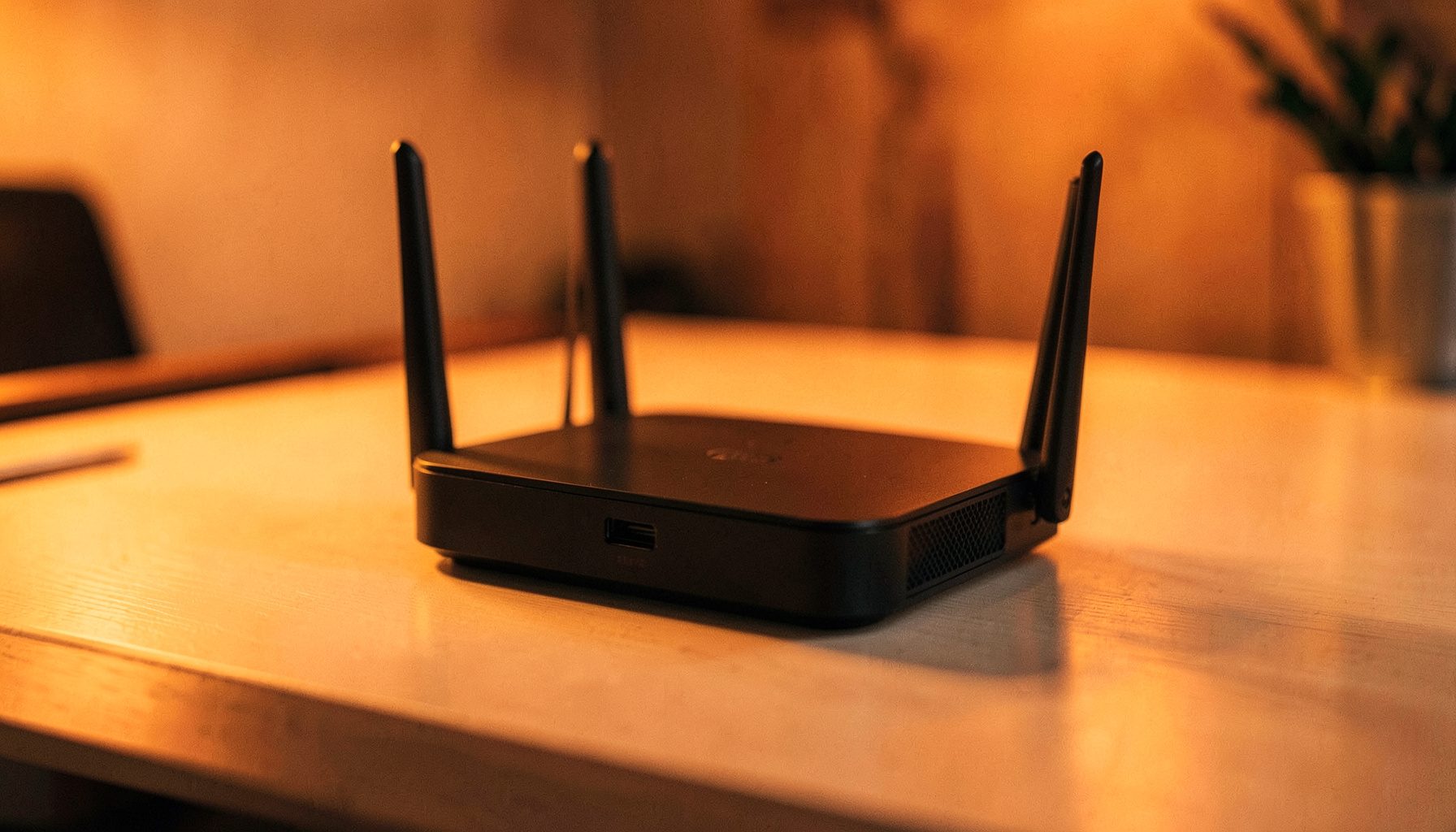 A modern wireless router with multiple antennas on a clean desk surface, warm ambient lighting, shallow depth of field