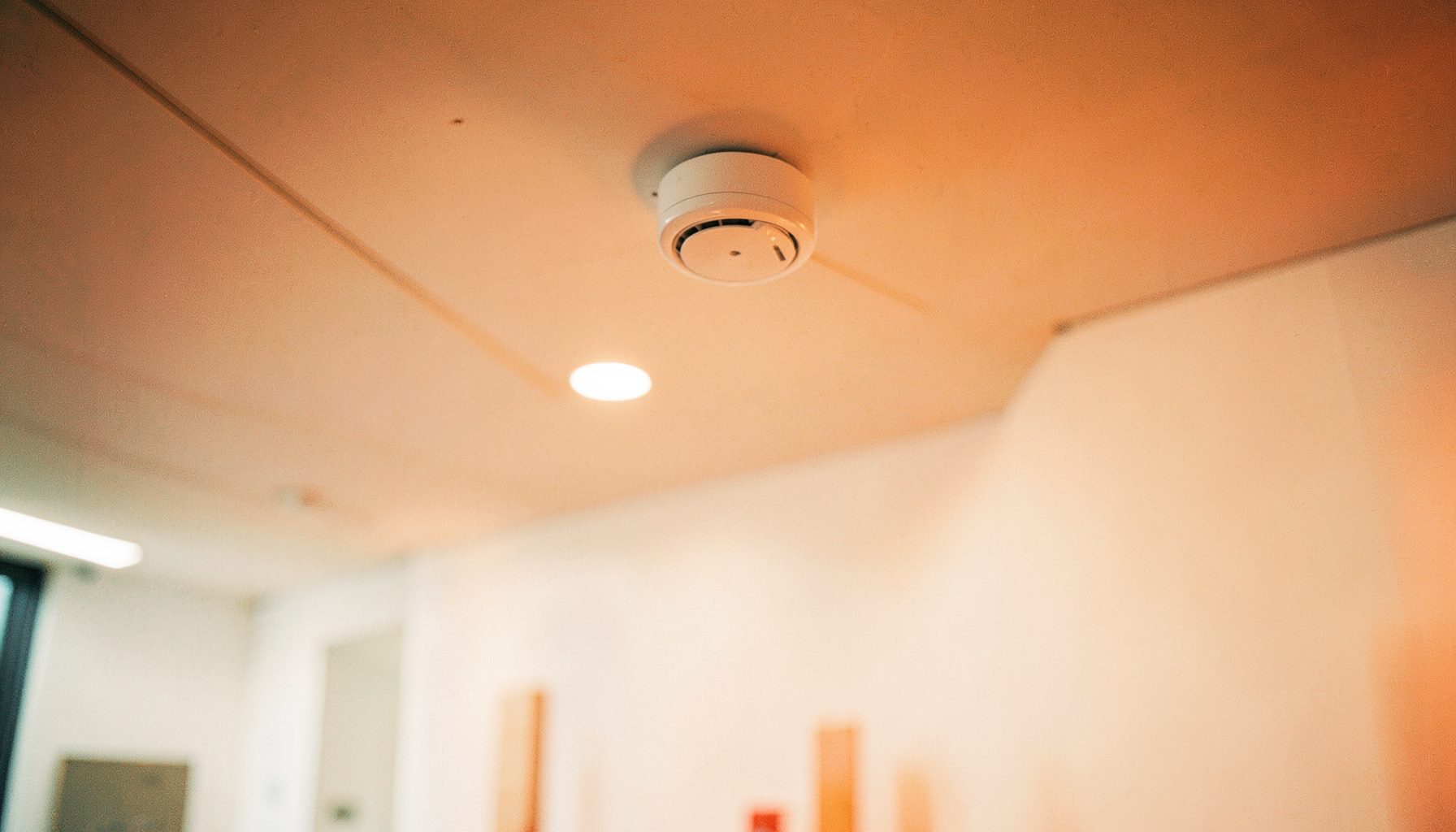 A ceiling-mounted wireless access point in a modern office interior, clean white walls, subtle overhead lighting